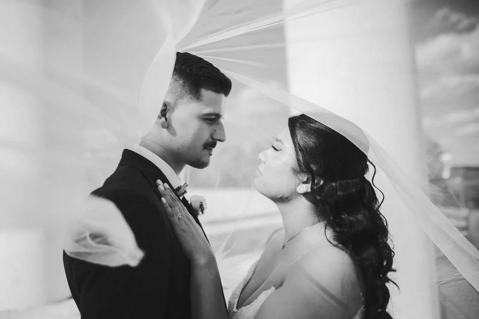 Couple de mariés en noir et blanc, voile emporté par le vent