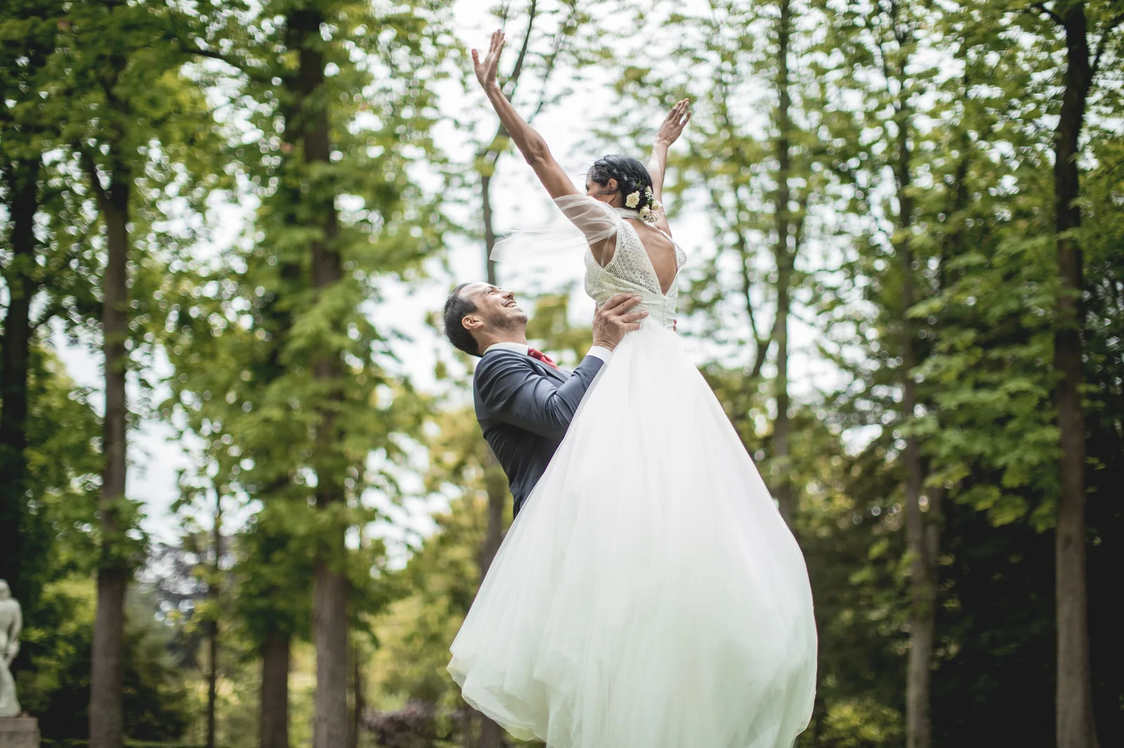 Le marié soulève la mariée sous les arbres d'un parc