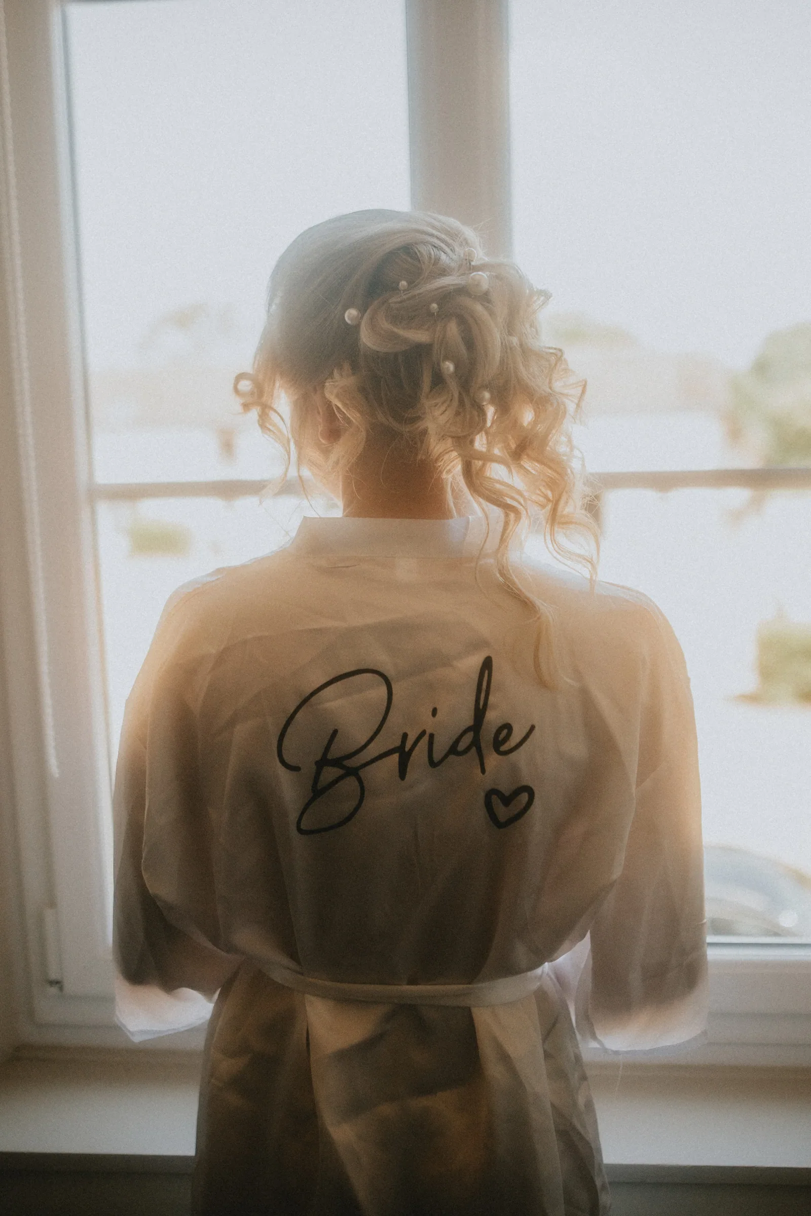 Mariée de dos portant une veste transparente floquée « Bride »