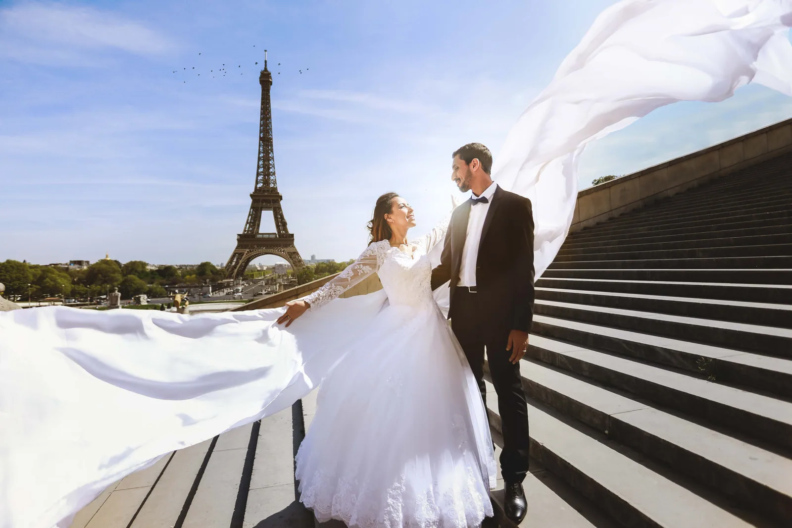 Les mariés au Trocadéro face à la tour Eiffel, voile emporté par le vent