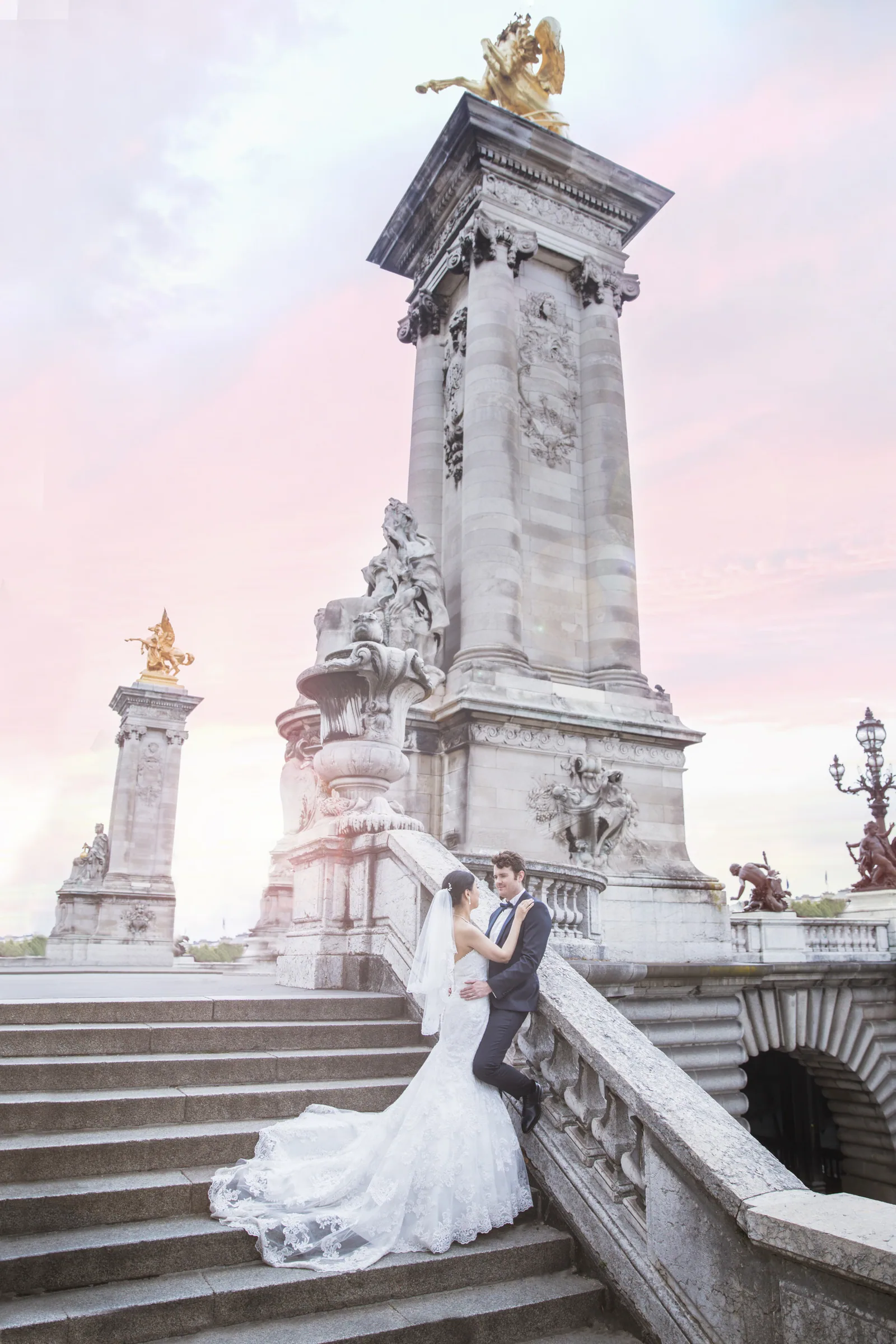 Les mariés sur les escaliers du pont Alexandre III sous un ciel rose